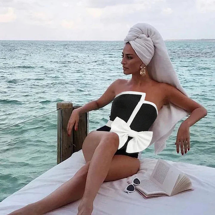 One-piece strapless swimsuit in a luxurious asymmetrical design with bow tie decoration combined with a matching skirt in monochrome colors - Gabriella