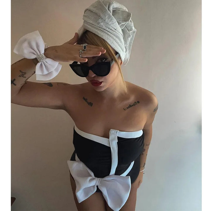One-piece strapless swimsuit in a luxurious asymmetrical design with bow tie decoration combined with a matching skirt in monochrome colors - Gabriella